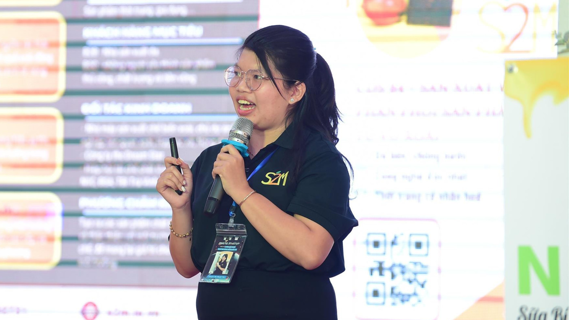 Ms. Thanh Vân, founder of the S2M Project, presenting on stage with a microphone at the VSIS 2024 event.